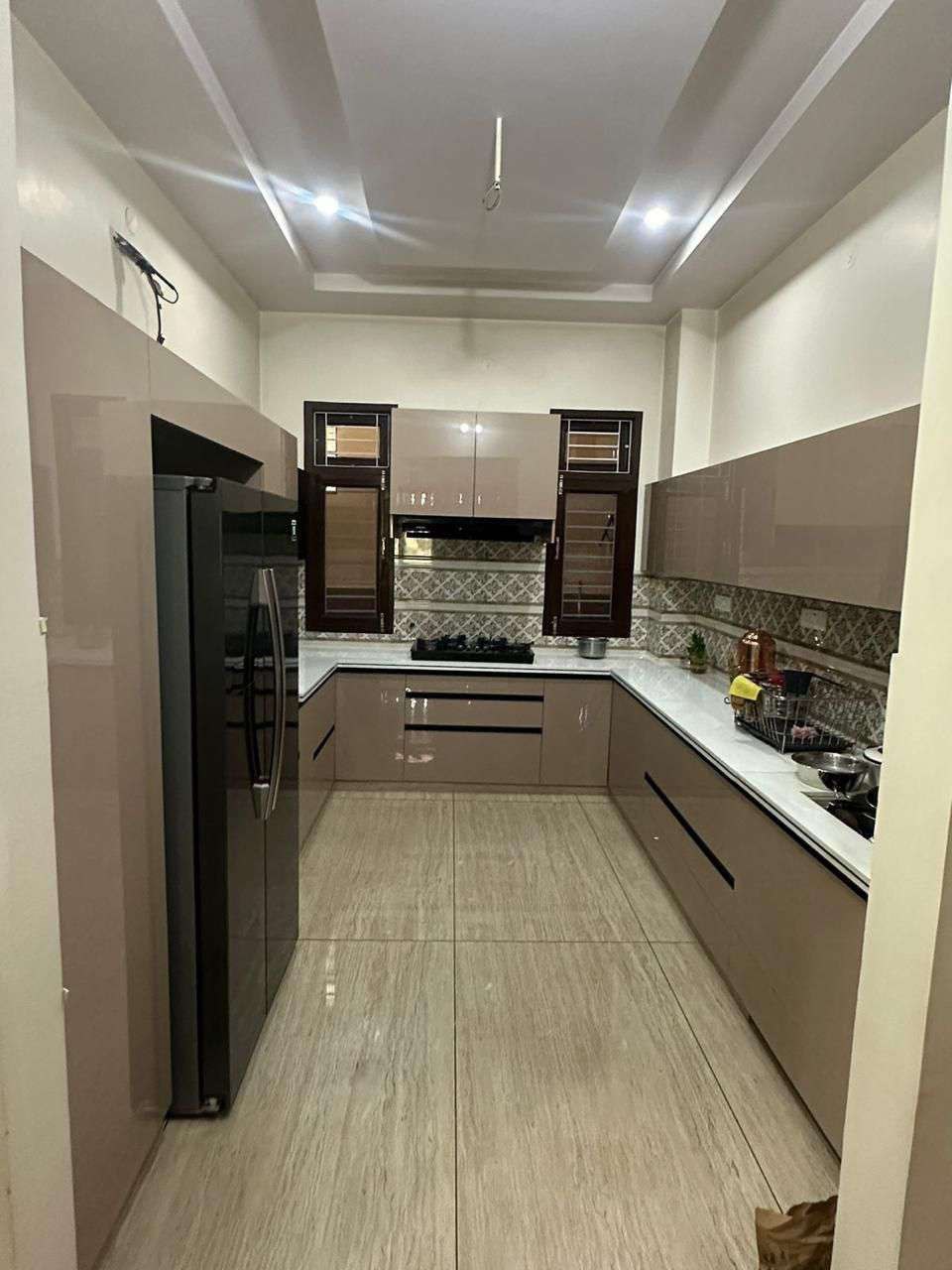 L-shaped modular kitchen in mocha finish with patterned backsplash